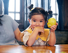 Beautiful Cute Asian Little Girl Eating Pear At The Table