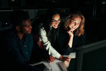 Group of happy diversity business people team working on project using laptop late in office at night