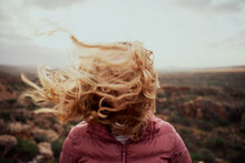 Closeup Of Young Woman Face Covered With Flying Hair In Windy Day Standing At Mountain