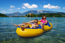 Boy And Girl On Inflatable Float In Lake. Little Children Floating In Yellow Raft On Surface Water.