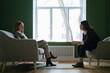 © Ivan Ozerov/Stocksy - two women sit opposite each other during a psychotherapy session