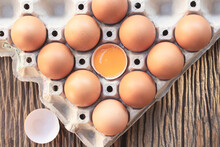 Chicken Eggs, Brown Eggs, Broken Egg In Carton Box On Wooden Rustic Table. Top View Eggs In Carton Box.