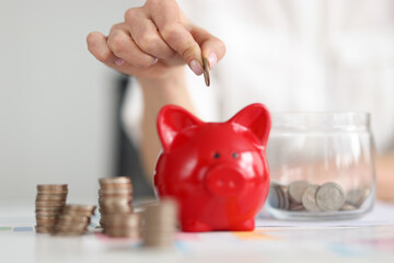 Womans hand putting coin in piggy bank closeup