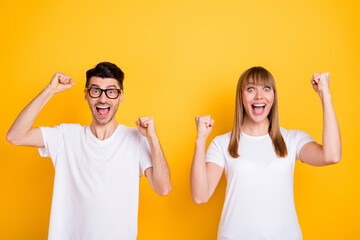 Poster - Photo of sweet lucky young couple wear white t-shirt spectacles rising fists isolated yellow color background