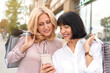 Two mature women looking at the phone and having fun while doing shopping