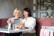 © Nastassia Yakushevic - Two mature women chatting and using the tablet device while having lunch in cafe