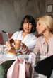 Two mature women chatting and using the tablet device while having lunch in cafe