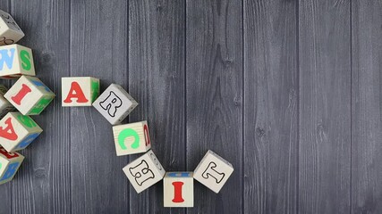Fototapete - Colourful wooden toy alphabet blocks spelling word - Architecture over a dark grey plank background with copyspace. Stop motion, top view