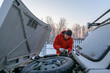© Danil Nevsky/Stocksy - Guy fixing car engine working in snowy rural yard