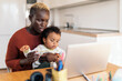 © Nunez Image/Stocksy - Mother using laptop while hugging her daughter