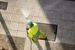 Worker cleaning a street sidewalk with high pressure water jet machine on sunny day. Copy space. Top view