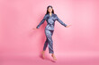 Full length body size photo of brunette wearing sleepwear jumping smiling isolated on pastel pink color background