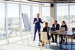 © Дмитрий Ткачук - Confident businessman makes a presentation of a new project in the boardroom at a company meeting. Beautiful auditors talk with different partners about the business using a whiteboard and graphs.