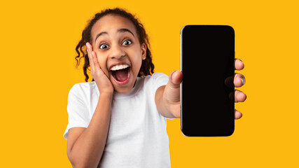 Excited black girl showing blank empty smartphone screen for mockup
