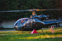 Civil Black Helicopter Getting Ready To Fly, Commercial Charter Private Copter At Helipad Airfield With People Embarking, Pilot, Getting A Pilot Course License Concept, Chopper Landing On Green Grass