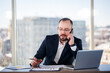 © DSMT - Adult male businessman, teacher, mentor looks at a laptop in his office. Office work. Development of a new business project