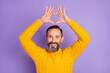 Photo of romantic bearded man raise hands show heart figure wear yellow pullover isolated violet background