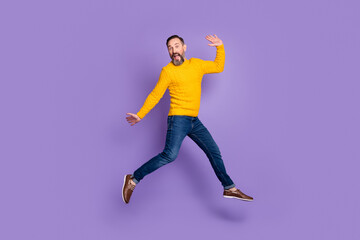 Sticker - Photo of excited man jump run raise hands wear yellow pullover jeans footwear isolated violet background