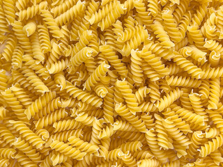 Food background or texture raw dry Italian pasta in shape of spiral. Closeup, macro, top view. Uncooked macaroni