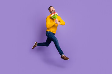 Profile photo of dreamy man jump run hold bunch flowers wear yellow sweater jeans shoes isolated violet background