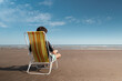 © Kevin - Young man sitting on a deck chair relaxing and enjoying the sunny day at the beach.