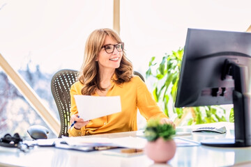 Shot of confident mature woman sitting behind her computer and working