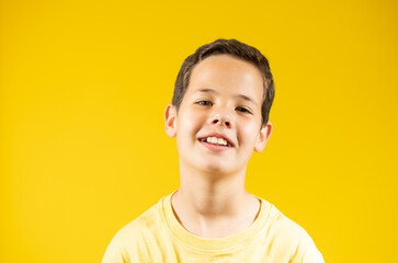 Portrait of happy boy smiling over yellow background