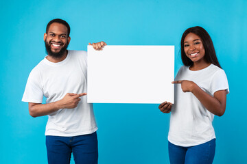Wall Mural - Black couple holding and pointing at blank white advertising placard
