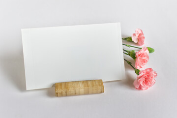 Mockup template with empty blank photo card and three pink flowers on white background.