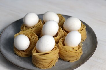 Sticker - Fresh white eggs in raw spaghetti nests on plate as ingredients for Easter pasta