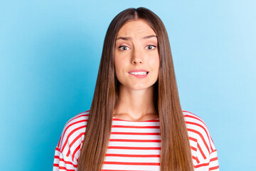 Wall Mural - Photo of pretty unsure young girl wear striped shirt biting lip isolated blue color background