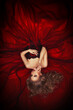 Portrait of a reclining beautiful blonde girl in a dark red ball gown