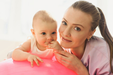 young mother and her happy baby having fun with gymnastic ball. gymnastics for kids on fitball.