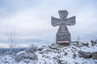Stone war cross near Lookout tower Stepanka on the border of Krkonose and Jizera Mountains. Winter overcast day, sky with clouds, trees covered with snow.