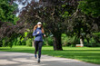 © skumer - Young woman jogging in park on sunny day