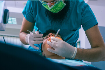 Wall Mural - The dentist is examining teenage boy's teeth in the dentist chair in the dental office