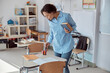 © Yaroslav Astakhov - Happy afro female teacher with book in a light elementary school classroom