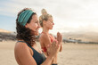 Two sportive women meditating and doing yoga at the beach