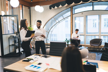 Wall Mural - Smiling diverse colleagues talking in modern office