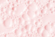Foamed surface of pink liquid soap, small bubbles, closeup