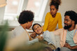 © bernardbodo - Afro parents and their children are socializing while sitting on the sofa in the living room