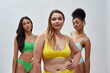 © Svitlana - Portrait of cute caucasian young woman smiling at camera while posing together with her female friends in colorful underwear isolated over light background
