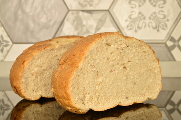 Two halves of fragrant white bread, close-up, on the background of tiles.