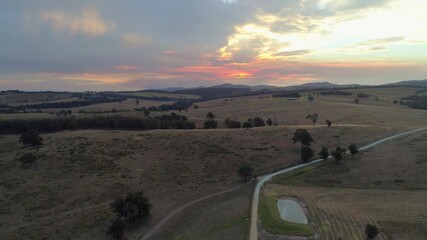 Wall Mural - Slow aerial rise over fields and hills revealing scenic sunset in Australian outback