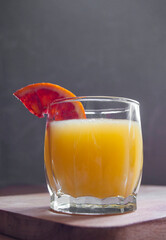 Wall Mural - A glass of fresh sweet blood oranges juice with a slice of a blood orange on a wooden cutting board.