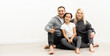 © Angelov - happy family father mother and children sitting on the floor in an empty white wall