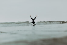 Young Male Surfer Doing Headstand On Surfboard In Misty Sea, Ventura, California, USA