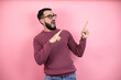 Handsome man wearing glasses and casual clothes over pink background surprised and pointing his fingers side