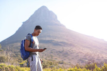 Young Male Hiker By Mountain In Table Mountain National Park Looking At Smartphone, Cape Town, Western Cape, South Africa