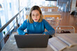 © Connect Images - Female higher education student typing on laptop in university cafe